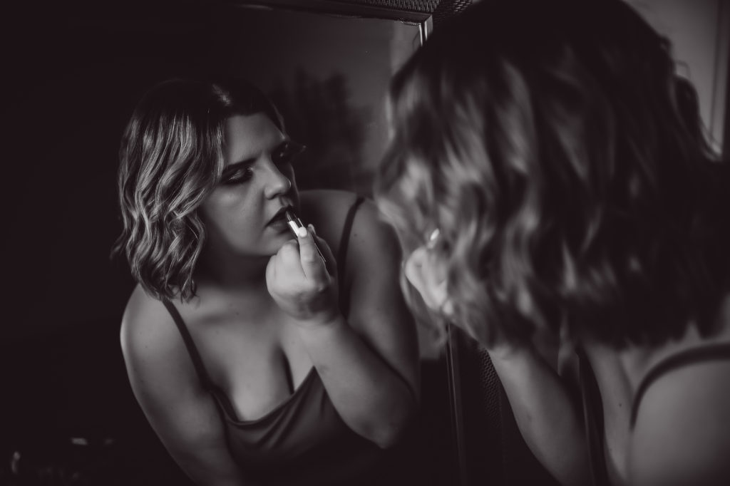 woman putting on lipstick for her Tennesse boudoir experience