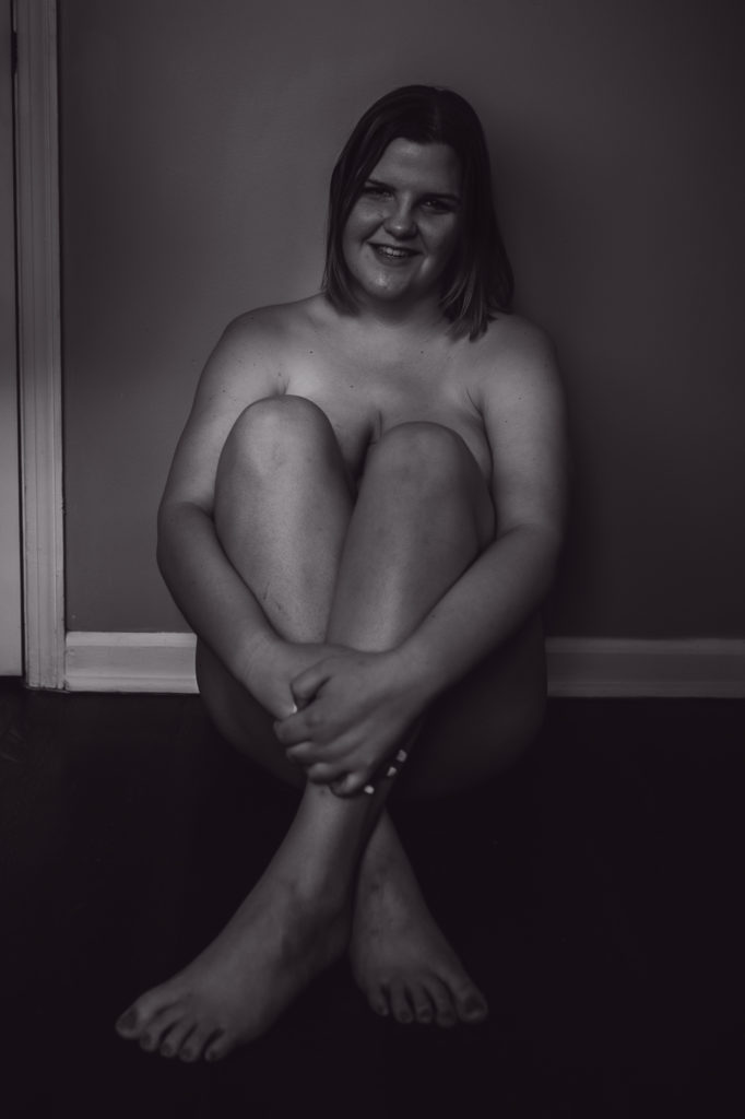 woman sitting against a wall with her knees to her chest for her Tennessee boudoir experience