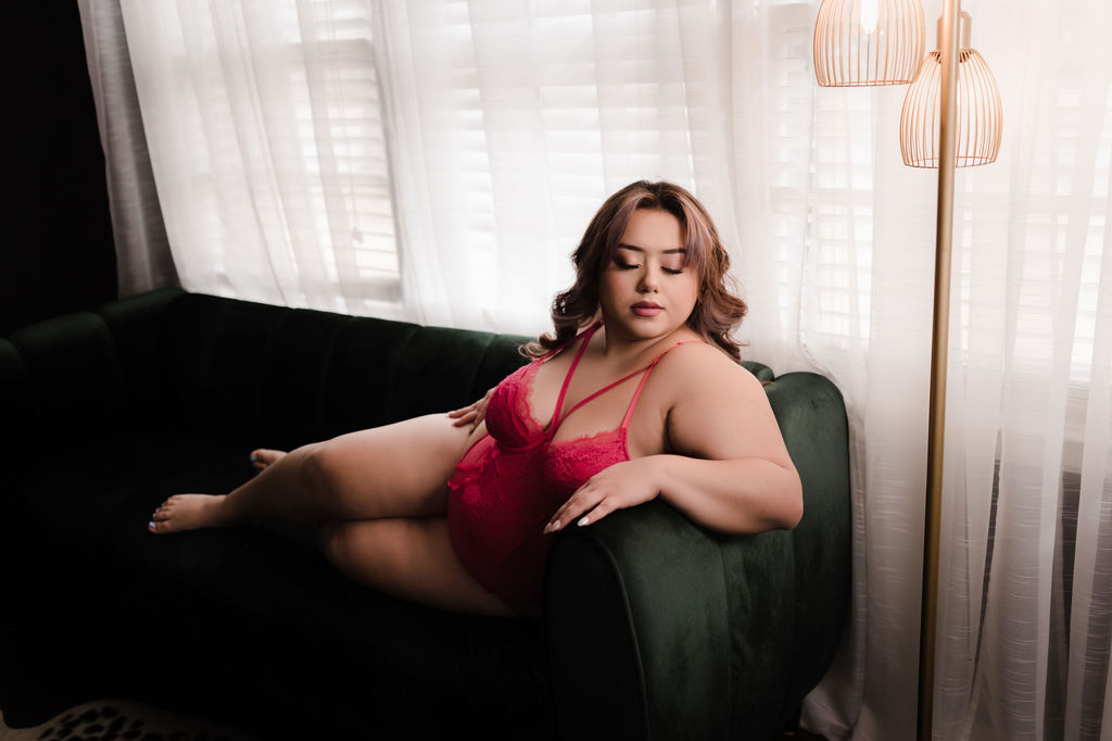 Woman in pink lingerie lays on a couch under a lamp