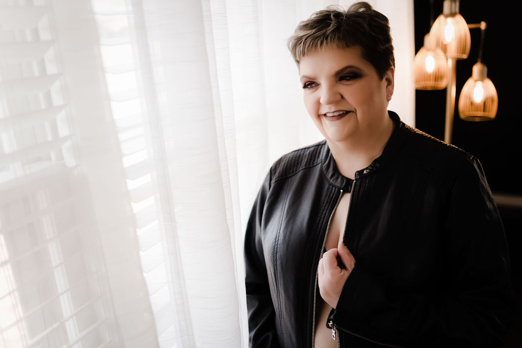 Woman stands by a window holding her leather jacket skin body memphis