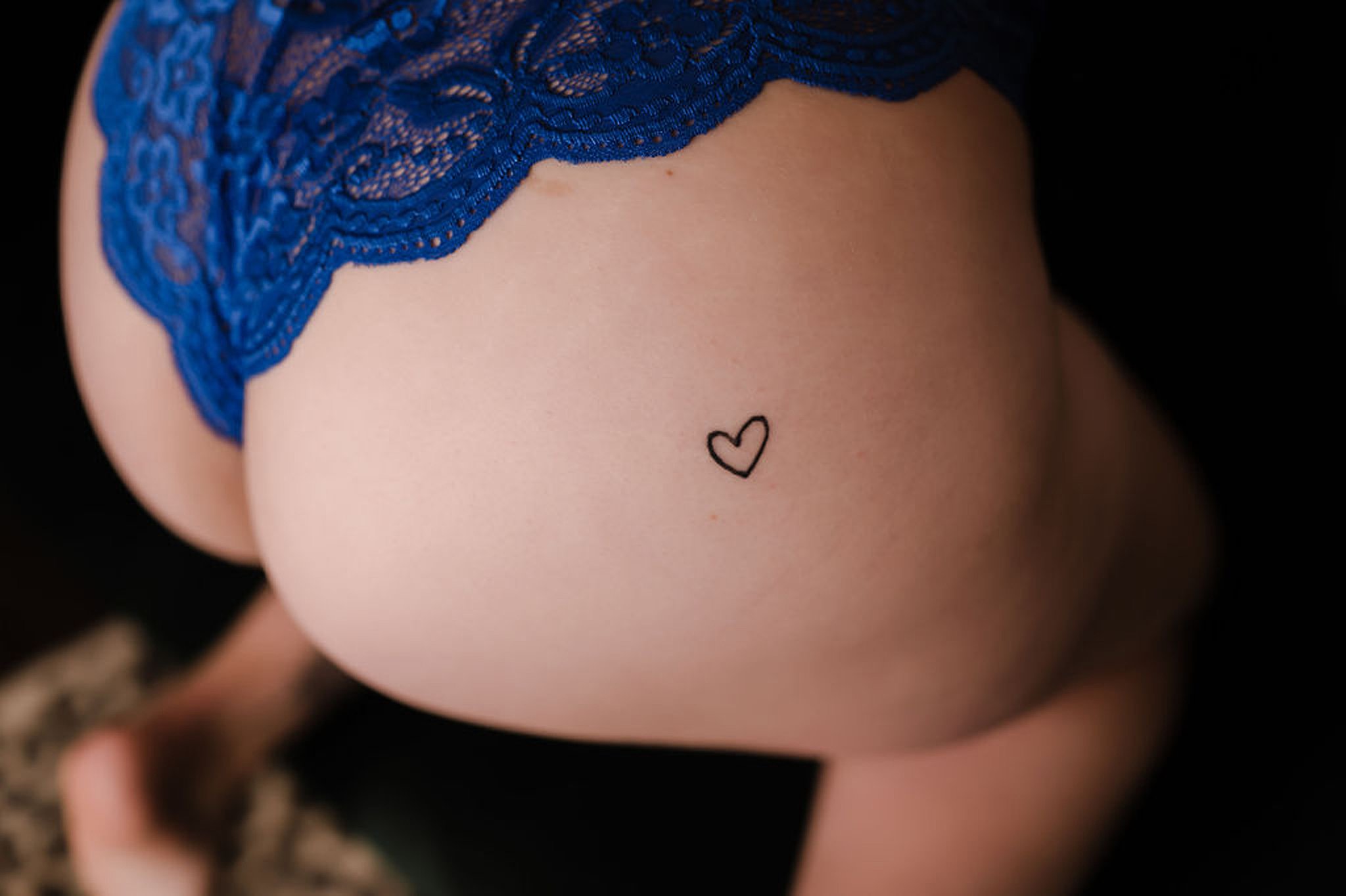 woman's backside with a small heart tattoo and blue lingerie