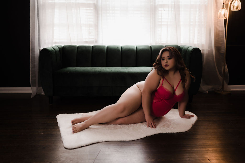 woman in pink lingerie lays on a white rug in front of a couch and window feathers spa