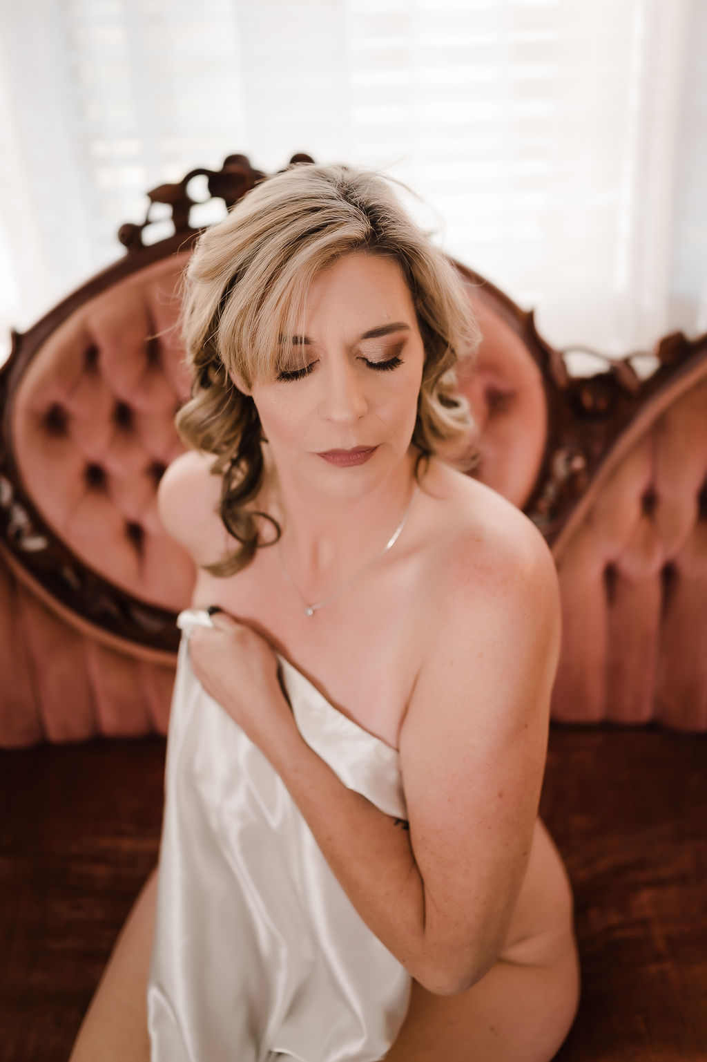 A woman sits on the edge of an ornate antique couch wrapped in a white silk blanket harbor town day spa