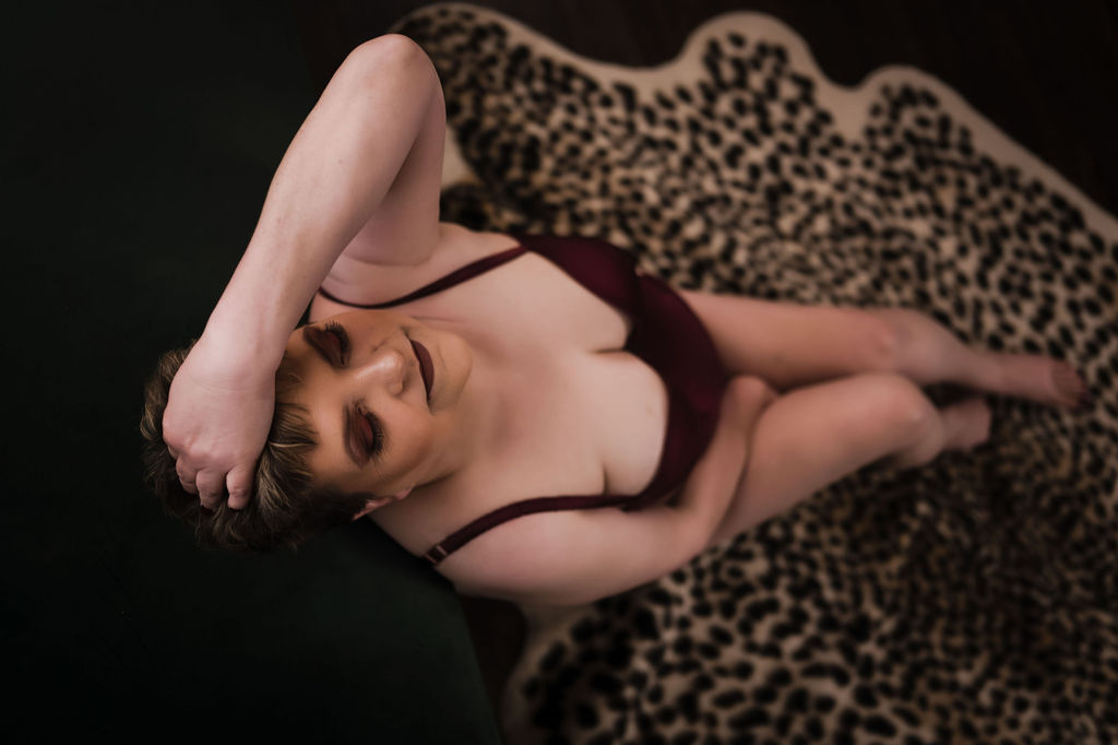 A woman in purple lingerie leans back on a stool with a hand in her hair