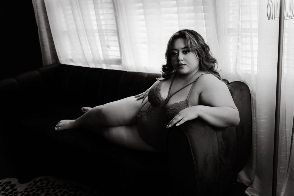 A woman in lace lingerie lays across a couch in front of a window skyline nailes collierville