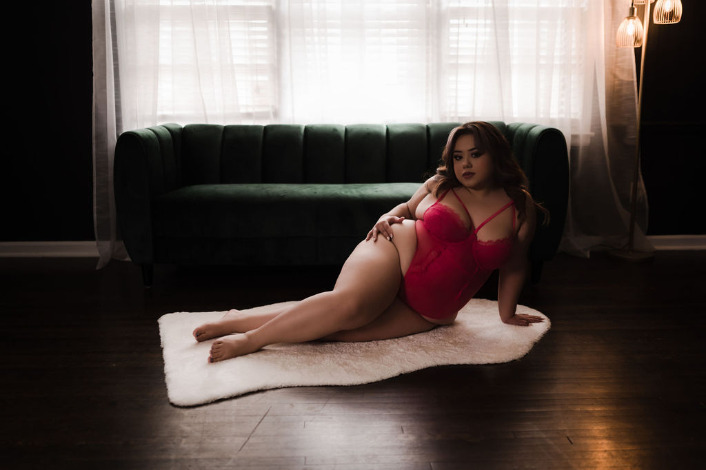 A woman in pink lingerie lays across a white rug in front of a couch and window upscale restaurants in memphis