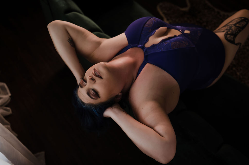 A woman in blue lingerie leans back onto a couch with hands behind her head de la belle spa