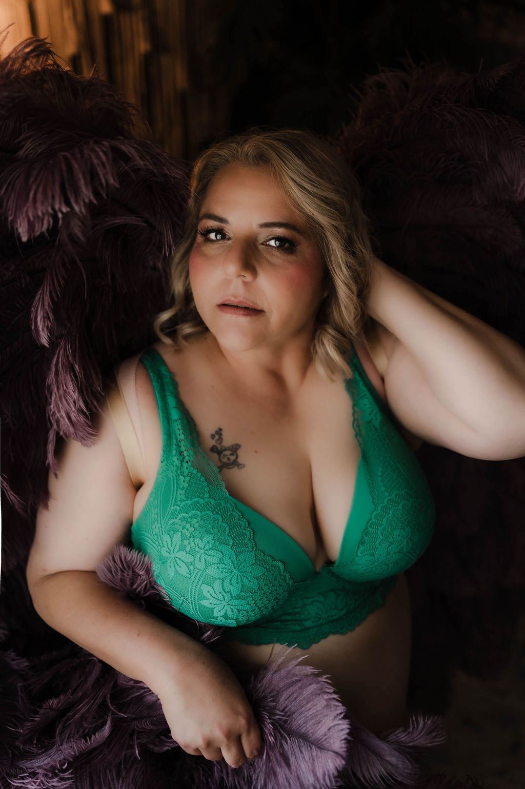 A woman in a green bra sits in a studio with a hand in her hair after visiting jonesboro hair salons