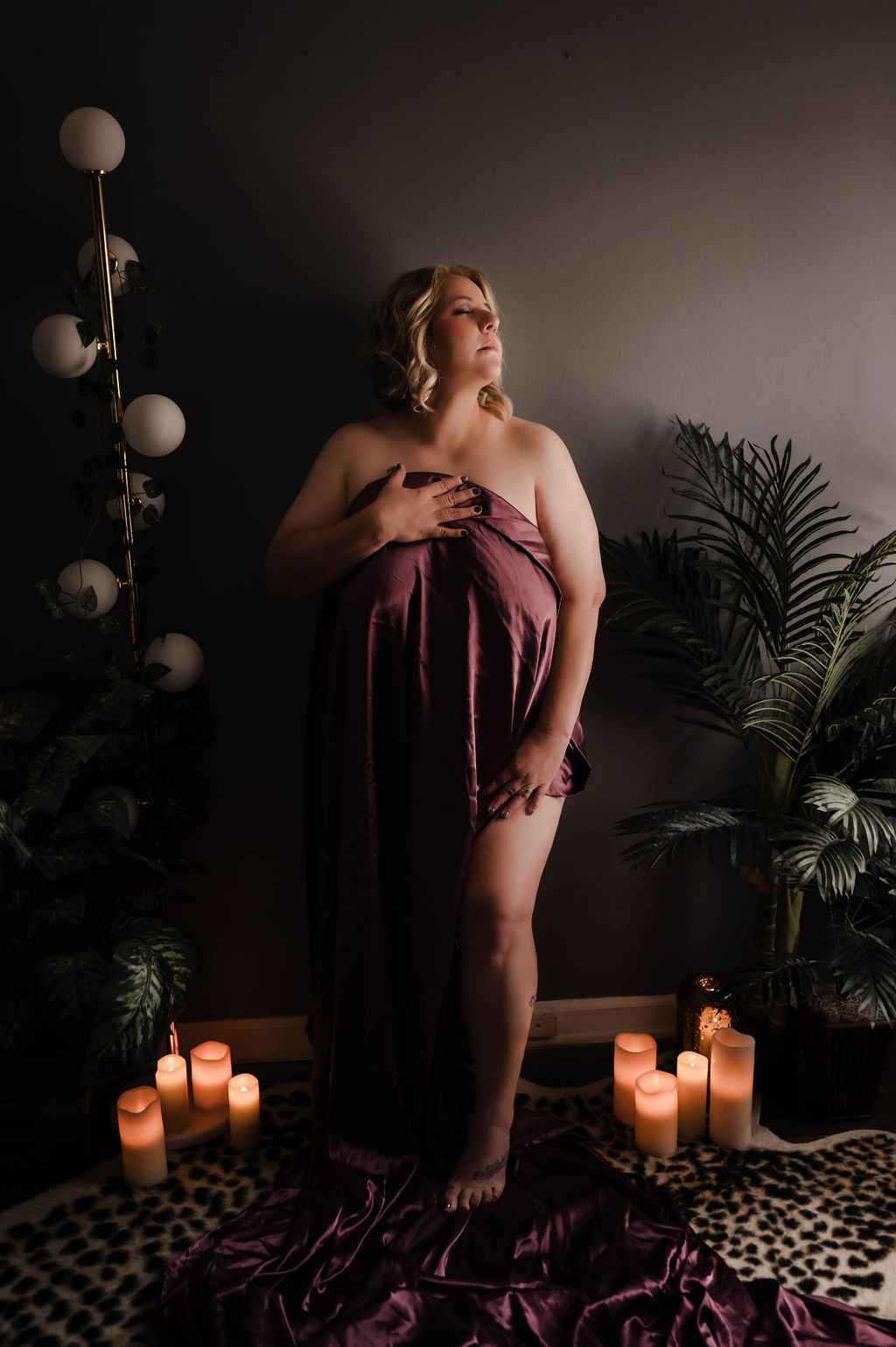 A woman covers herself in a silk sheet while standing in a studio after visiting jonesboro hair salons