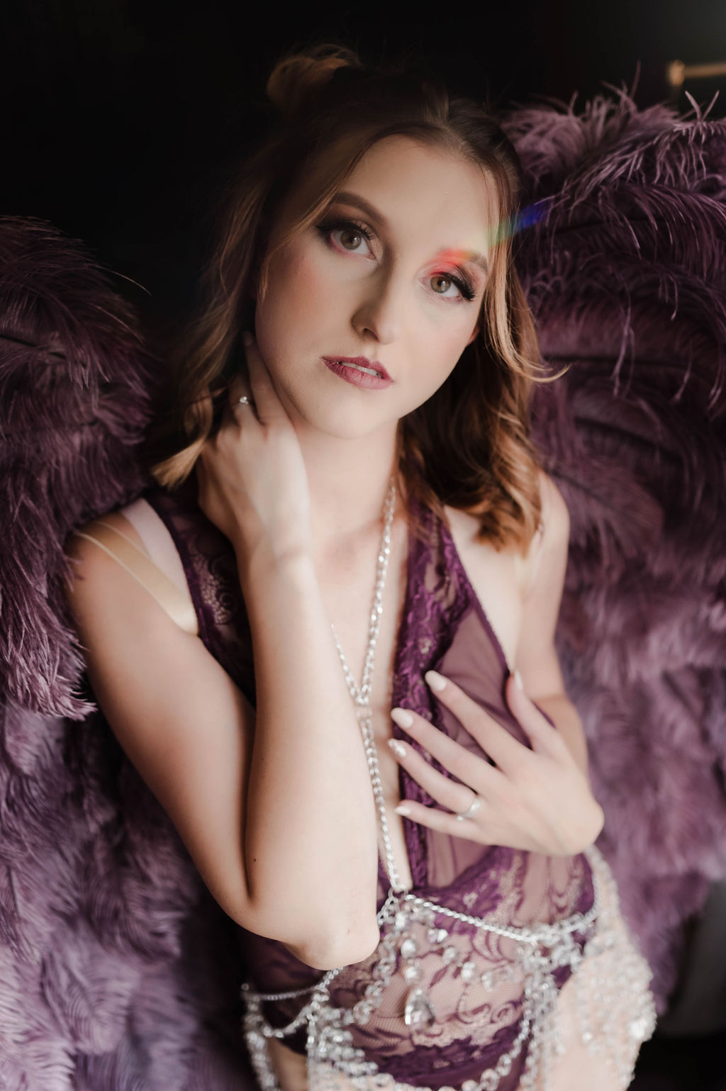 A woman in purple lace lingerie stands in a studio with matching purple feather wings after some brunch jonesboro ar