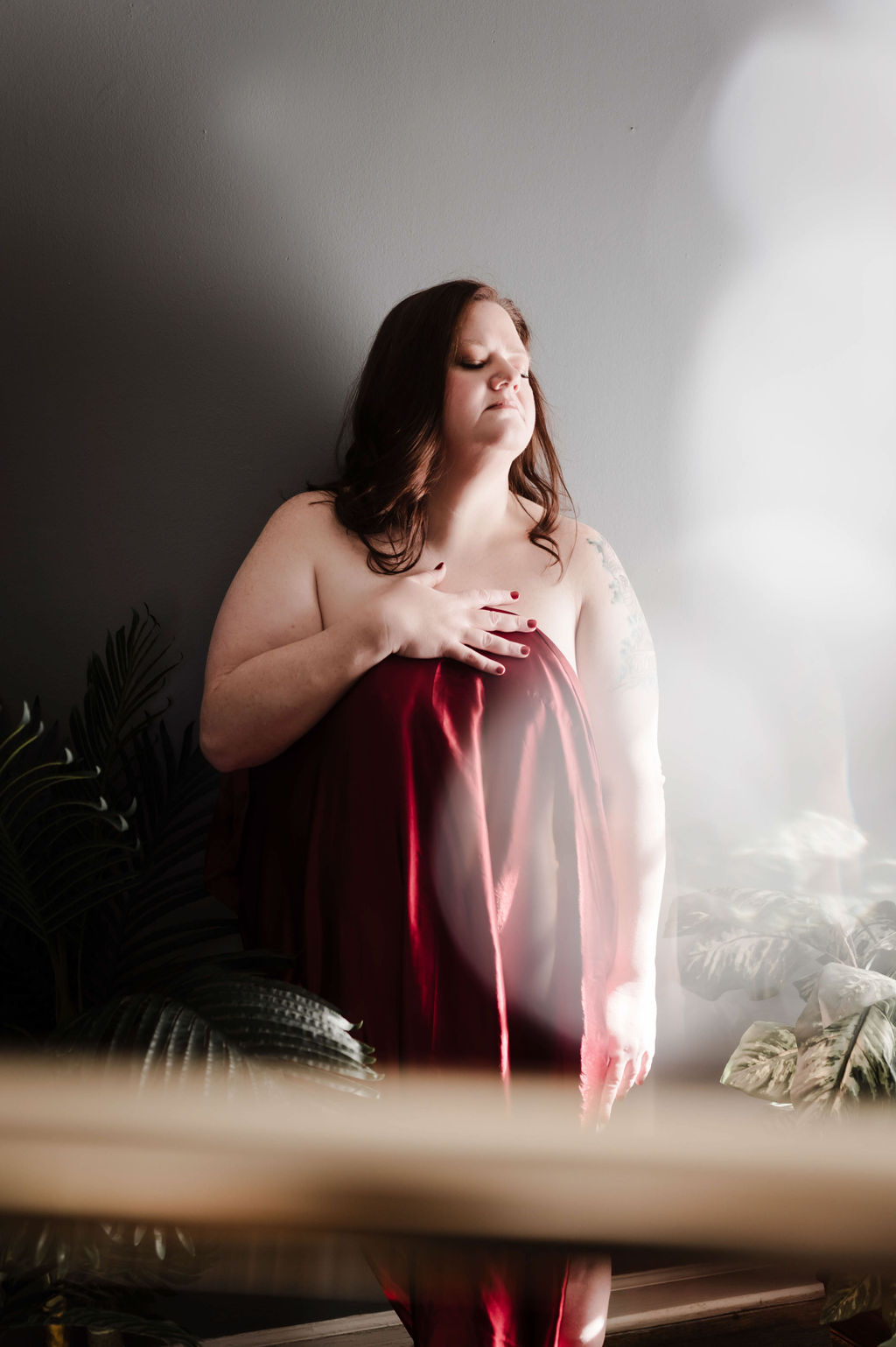 A woman stands against a wall covering with only a red sheet in a studio after visiting a spa hernando ms